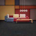 Modern living room with blue armchair, red sofa, white coffee table, and wall art on a dark carpet