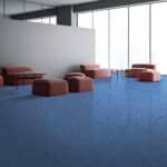 Modern lounge with blue carpet, white walls, and several brown upholstered benches by large windows