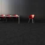 Minimalist room with a low white table and red stools against a dark wall.