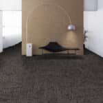Minimal room with a low bed, black cushion, and white lantern against a wood-paneled wall.