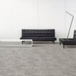Minimal waiting room with a black bench, small white table, and gray carpet against a white wall.