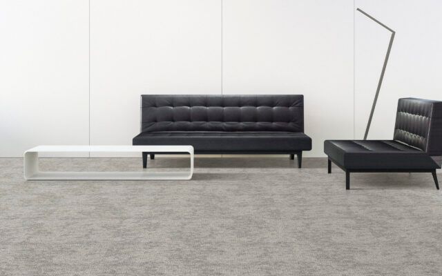 Minimalist living room with black sofas, white coffee table, and gray rug