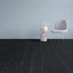 A small white chair beside a white side table on a dark floor against a gray wall.