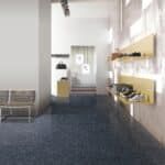 Modern lobby with blue carpet, white walls, seating, and wall-mounted shelves along the right side.