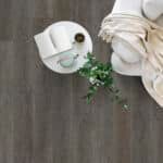 White ceramic cups and folded napkins with green leaves on a dark wood table.