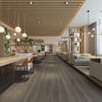 Modern restaurant interior with wooden tables, pendant lights, and gray chairs in a bright, airy space