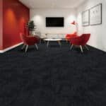 Modern conference room with red chairs, white table, wall-mounted TV, and dark carpet.
