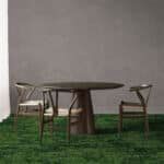 Small round table with three chairs on a green rug against a plain gray wall.