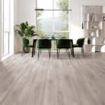 Bright dining room with a round table, dark chairs, large window, and light wood floor