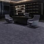 Modern lounge with two gray chairs, a dark desk, and backlit shelving in a dim room