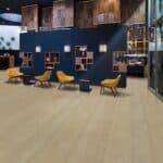 Modern lounge with mustard chairs, blue walls, and a reception desk in a spacious interior.
