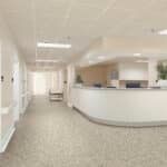 Empty hospital or clinic lobby with white walls, speckled floor, and a curved reception desk.