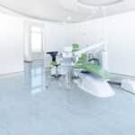Bright white dental clinic with an exam chair, sink, and modern equipment