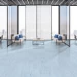 Modern lobby with blue chairs, glass walls, and a small table on a light blue floor