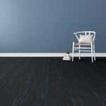 White chair beside a small lamp on a dark floor against a blue wall.