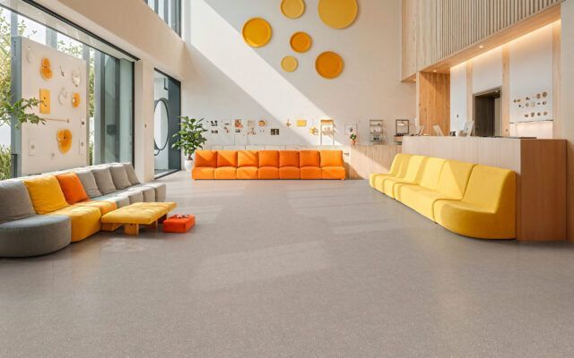 Bright modern lounge with orange and yellow sofas, large windows, and playful wall decor