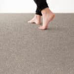 Bare feet walking on a gray carpet from a low angle