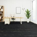 Minimal white office with desk, chair, wall art, and a tall potted plant on dark carpet.