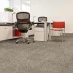 Office with two chairs, a desk, and gray carpet; one chair is black, the other red.