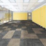 Empty office room with yellow walls, carpet tiles, and glass partitioned windows