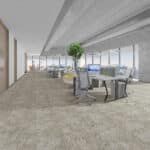 Bright modern office lounge with tables, chairs, and a potted tree near large windows