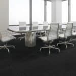 Modern conference room with white chairs around a long table beside large windows