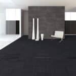 Minimal modern interior with dark floor, gray wall, white chair, and tall white vases.