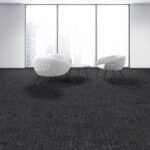 Minimalist room with two white chairs on a dark carpet in front of large windows.