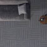 Top-down view of a gray patterned floor with a small white stool and a round orange object at the edge.