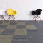 Two modern chairs, one yellow and one black, on a gray checkered carpet against a white wall.