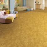 Spacious room with gold carpet and a patterned sofa by a window