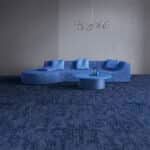 Blue sectional sofa in a gray room with a dark blue carpet.