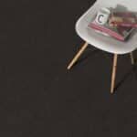 Small white table with wooden legs holding a book or magazine on a dark surface.