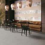 Modern cafe with wooden tables and chairs, pendant lights, and a large mural wall.