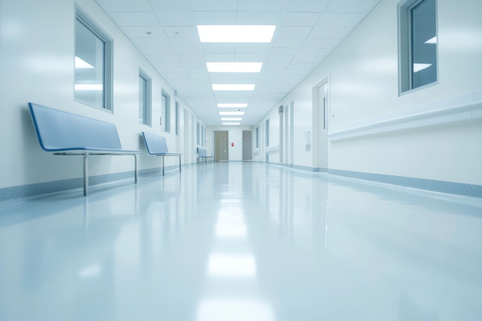 Bright, empty hospital corridor with glossy white floors and blue accents