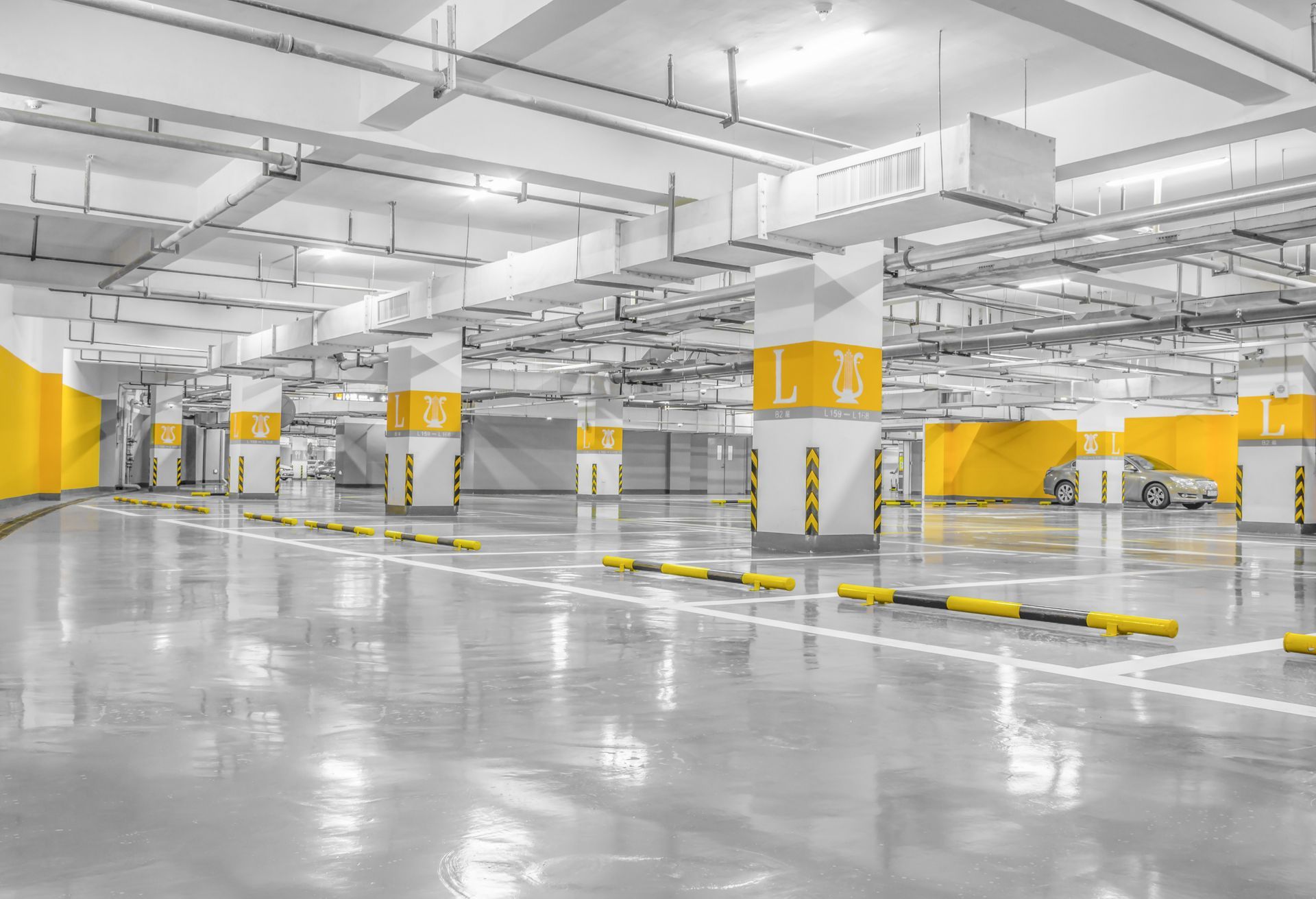 Empty underground parking garage with yellow-striped pillars and glossy concrete floor