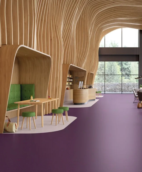 A spacious, modern building lobby with a curved glass wall, polished concrete floors, and round support columns.