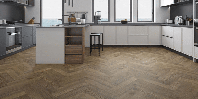 Modern kitchen with white and dark gray cabinets, a wooden kitchen island with stools, and herringbone wood floors.