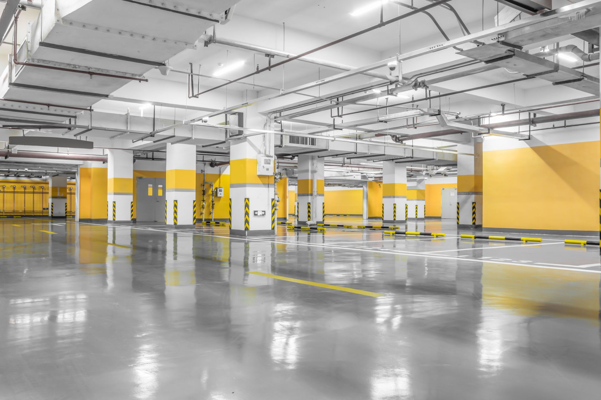 Empty underground parking garage with yellow pillars and polished concrete floor