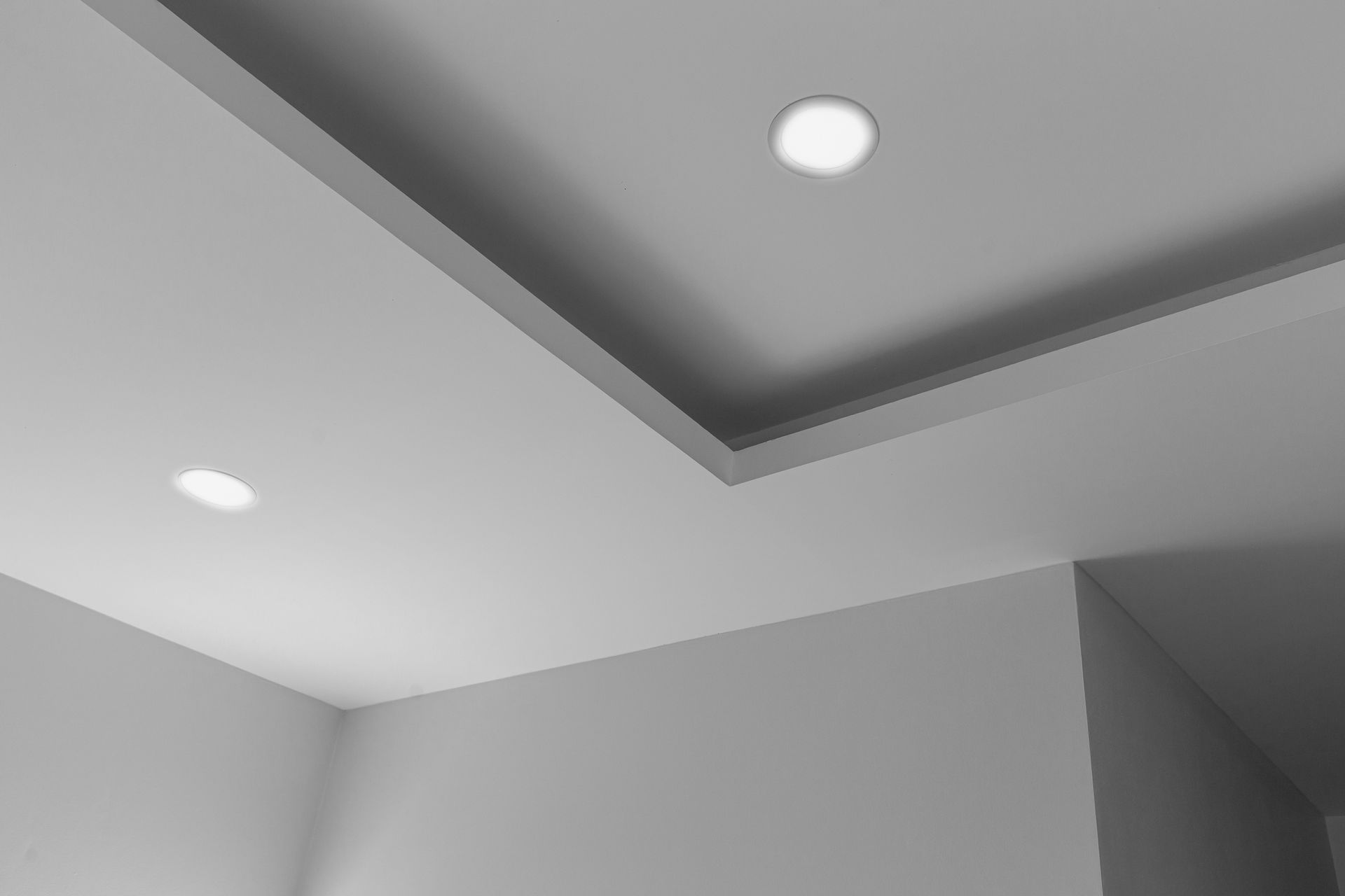 Gray room ceiling corner with recessed lights and layered trim.