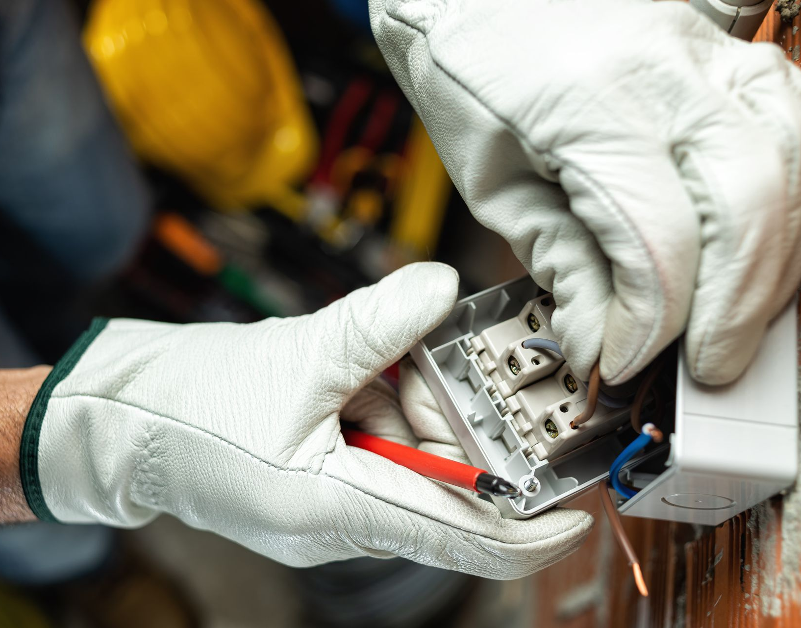 Gloved hands repairing an electrical switch with a screwdriver and wires