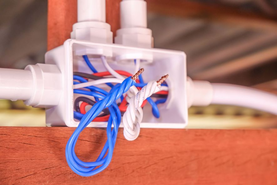 Close-up of tangled blue, red, and white wires inside a transparent electrical box
