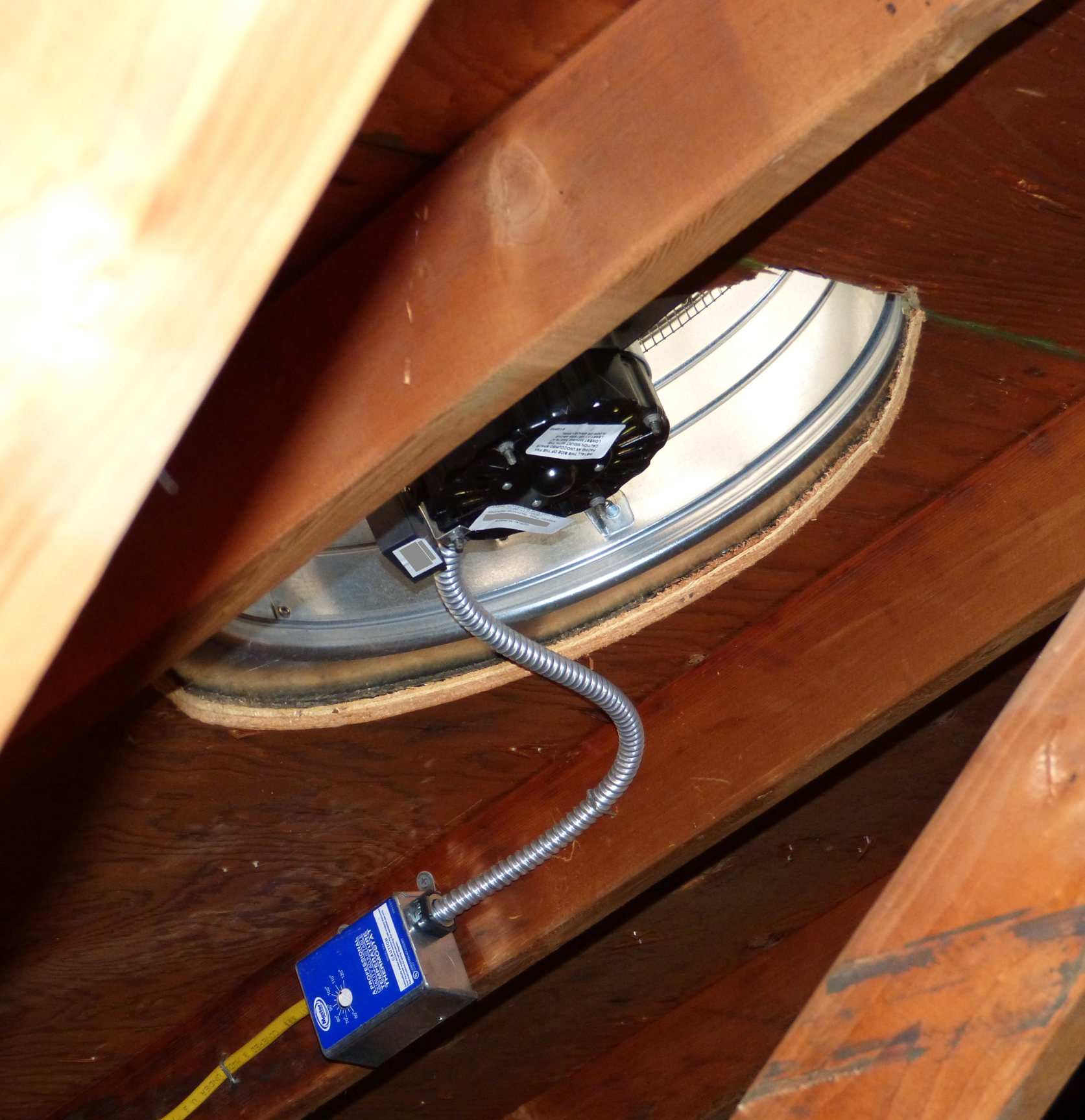 Two metal roof vents on a flat rooftop with trees in the background