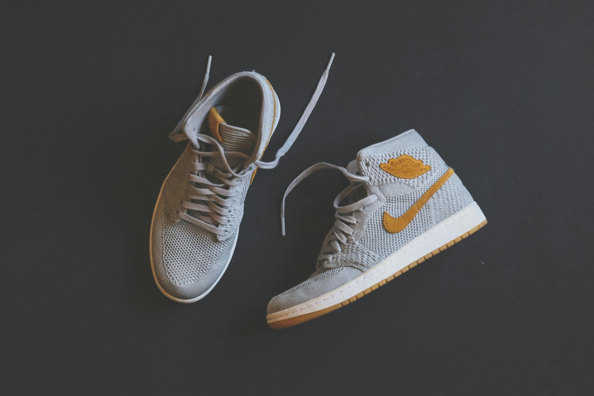 Gray and gold high-top sneakers on a gray background.