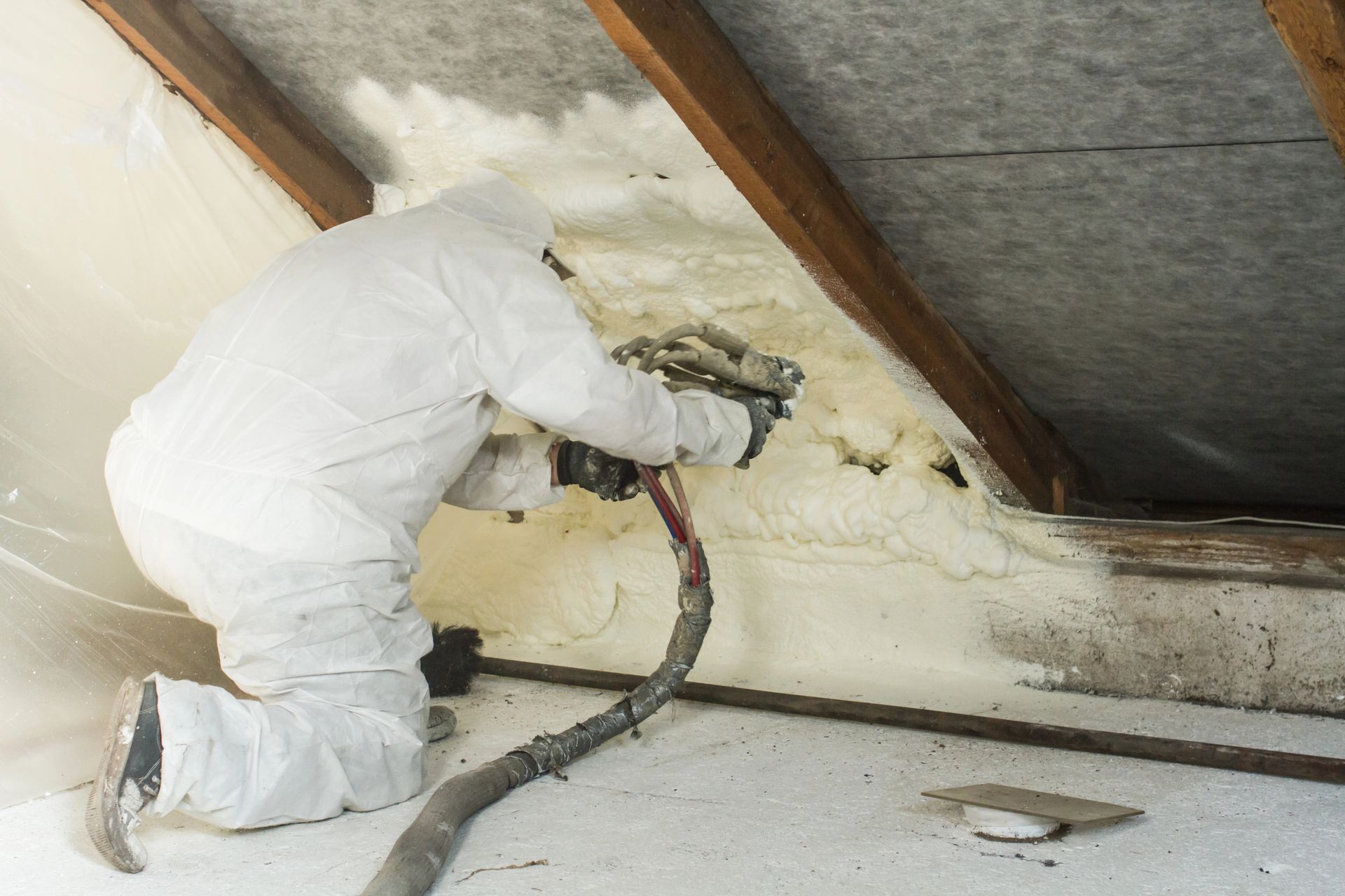 Spray foam insulation being applied to a wall by a trained installer during a residential insulation service.