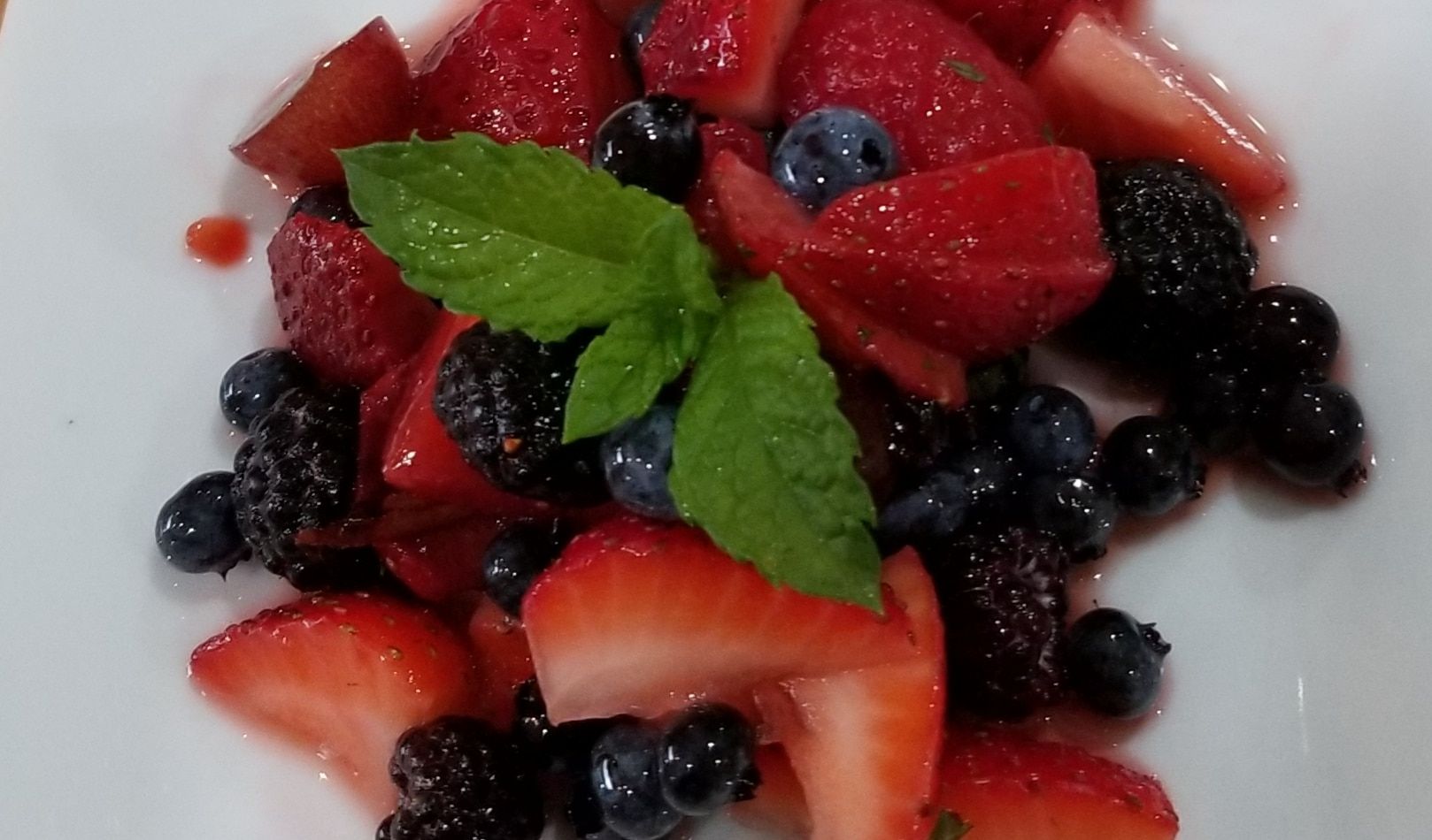 A white plate topped with strawberries blueberries and blackberries