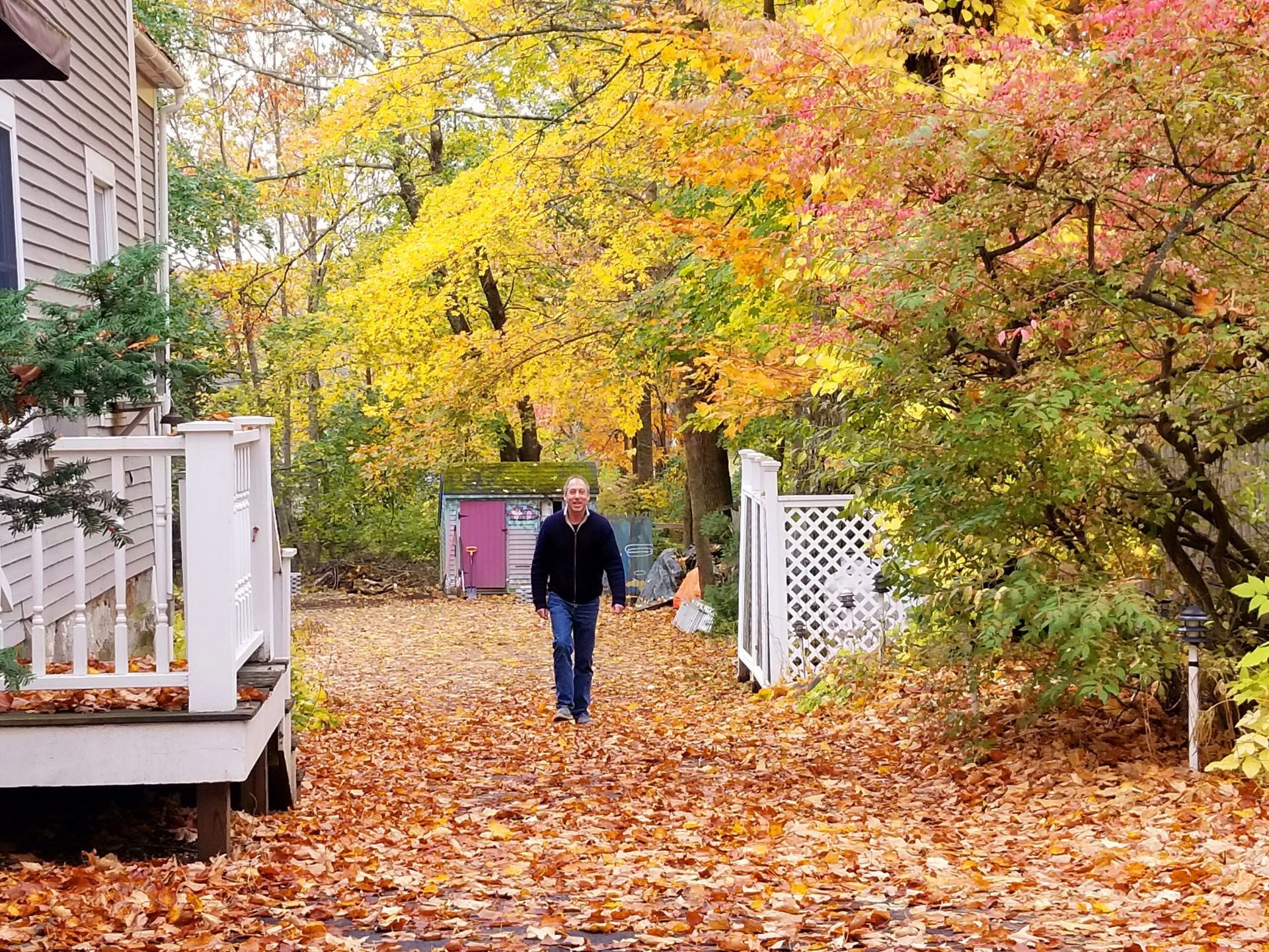 A man is walking down a path covered in leaves.