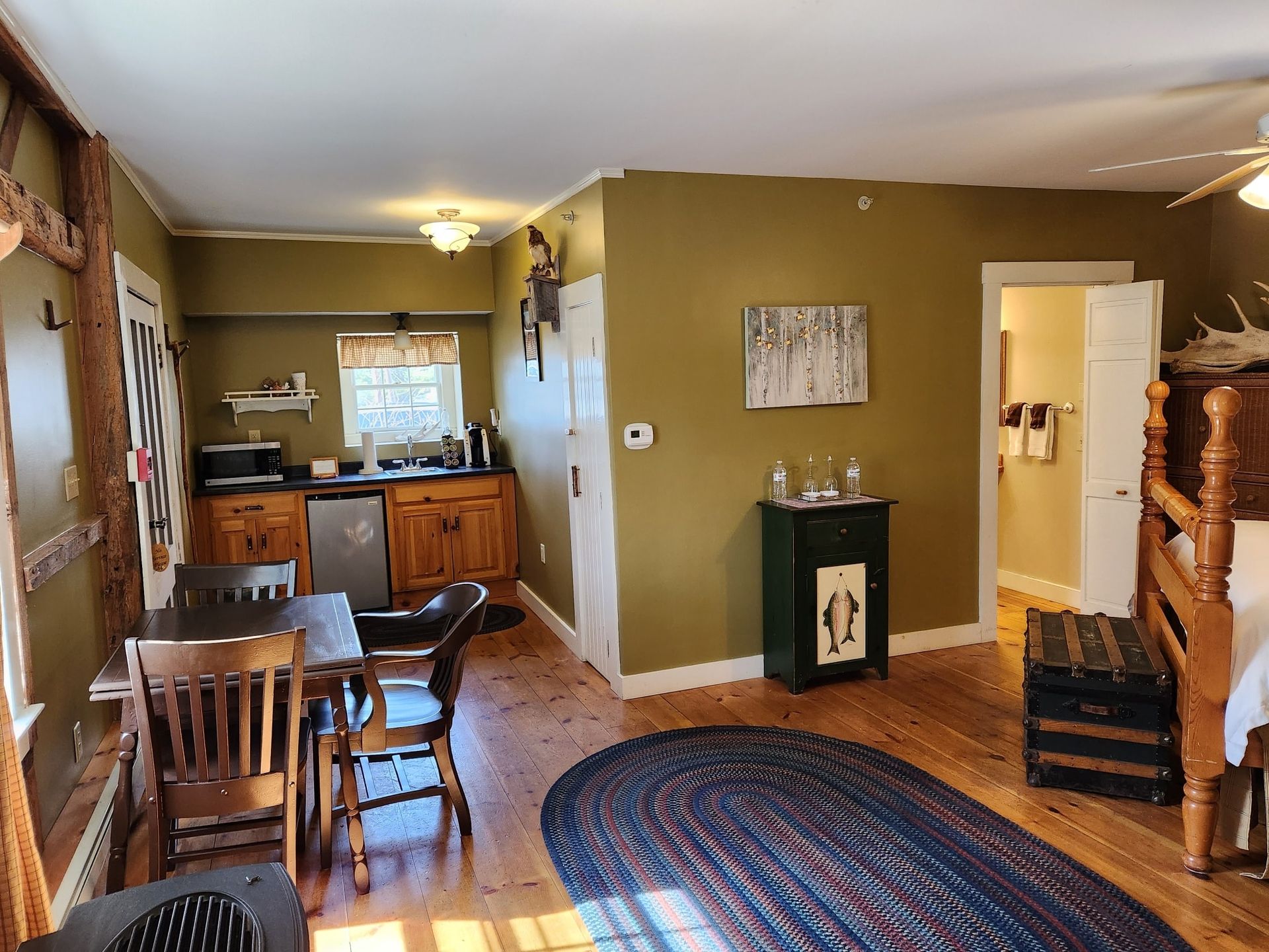 A living room with a table and chairs and a rug on the floor.