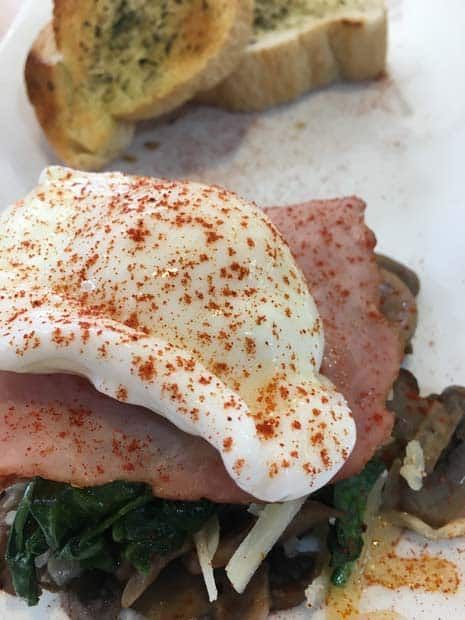 A close up of a sandwich with ham and eggs on a plate