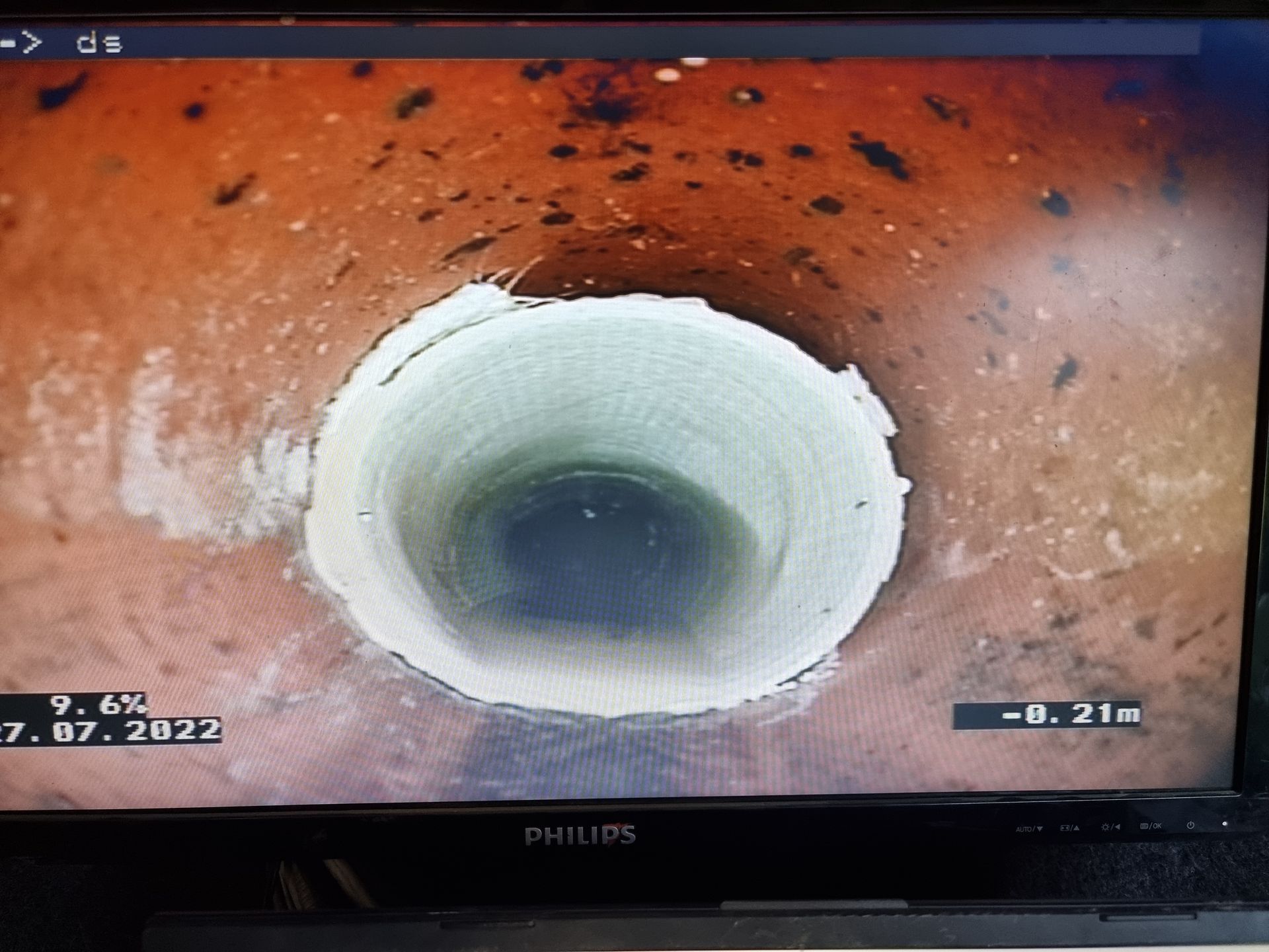 View inside a cylindrical hole. A white ring surrounds a dark blue center. The hole is set in reddish-brown dirt — Pro Pipe Solutions in Queanbeyan, NSW